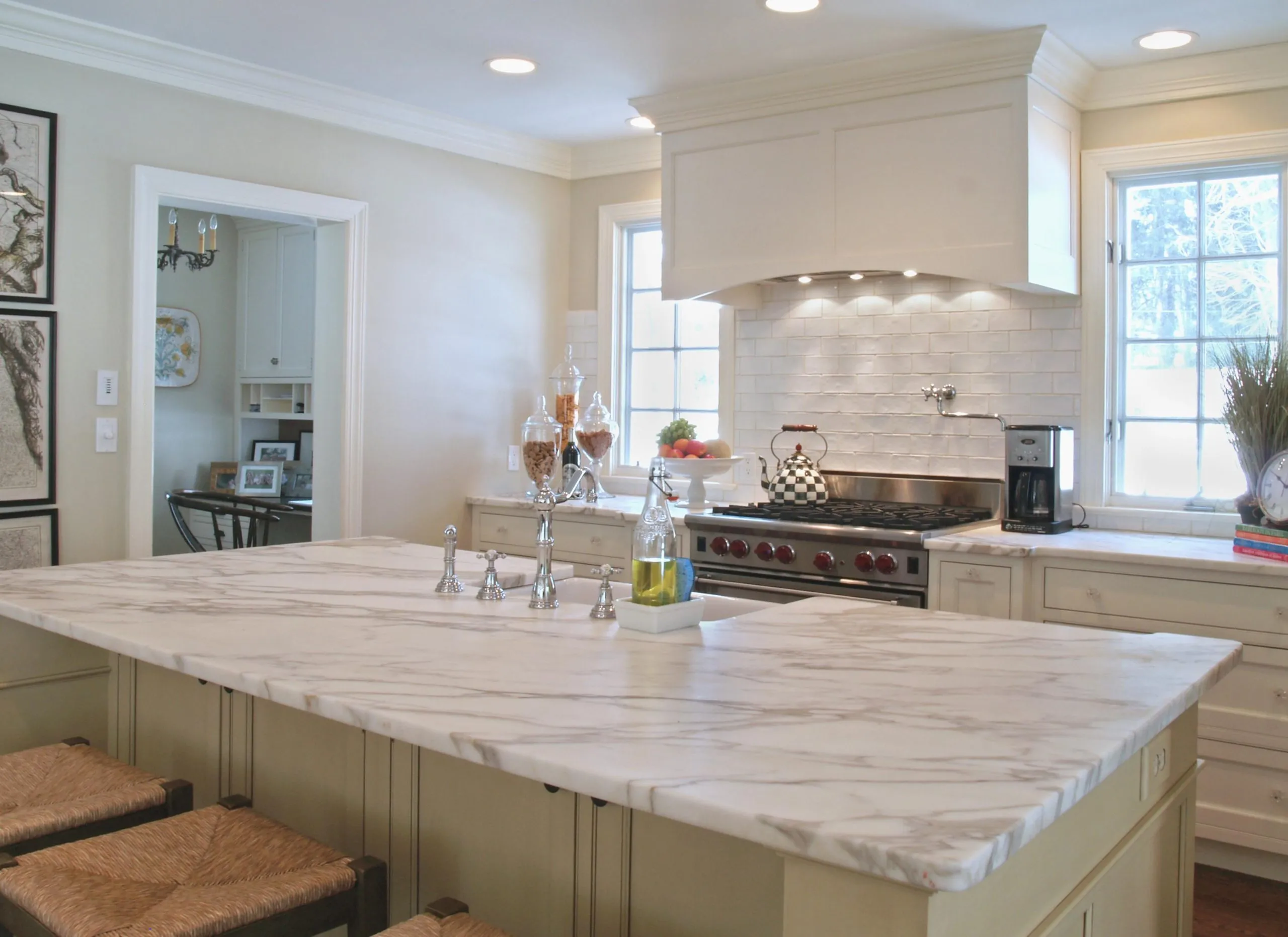 Marble kitchen island with white cabinetry by Amici Stone